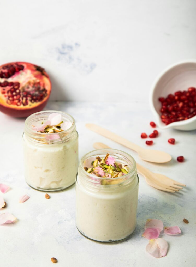 Delicious homemade yogurt parfait topped with pomegranate and pistachios, styled on a light background.